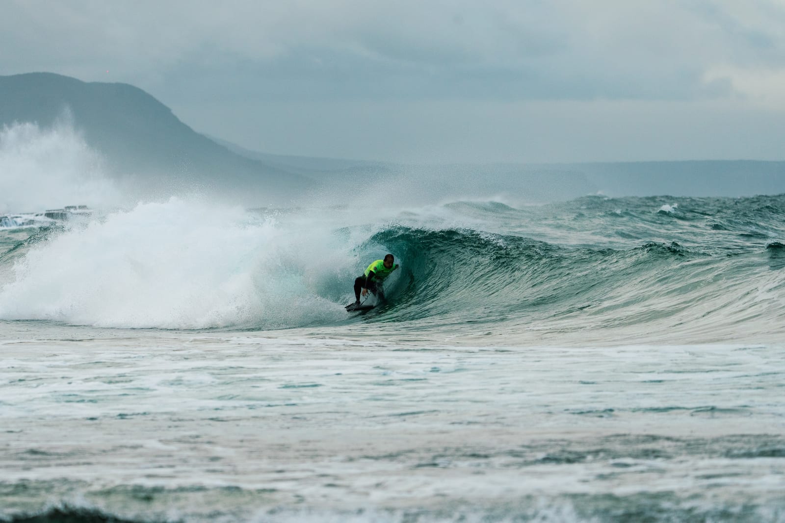 A rider in a competition jersey deep inside a breaking wave